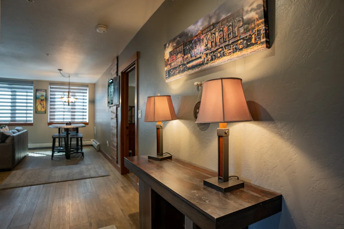 An intimate dining area illuminated by warm lighting, featuring a modern dining table surrounded by chairs and accented by tasteful artwork. The setting is cozy and inviting, creating the perfect backdrop for games, meals, or story-sharing sessions.