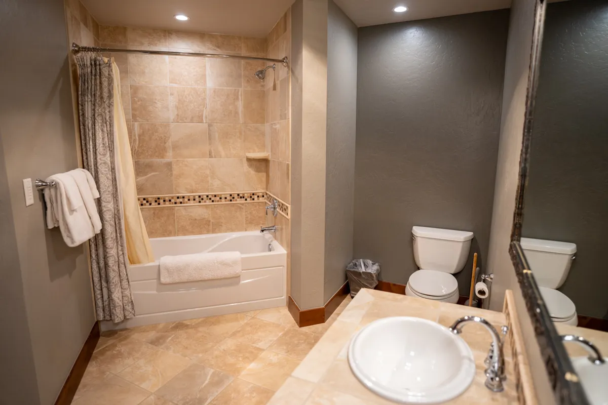 A calming bathroom featuring a bathtub, sink, toilet, and fluffy towels, offering a sanctuary for self-care and relaxation after a day outdoors.